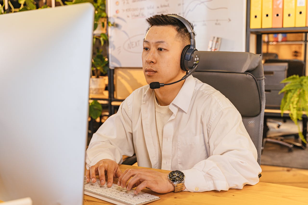 Man with headset working on computer in a modern office setting.